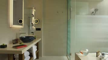 Un baño moderno con tocador de madera, un espejo grande y una cabina de ducha de vidrio.