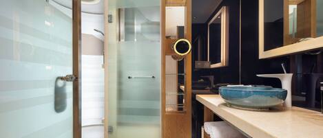 A modern bathroom with a glass shower door, a wooden vanity, and a large mirror.
