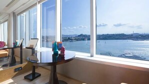 Habitación moderna con ventanas amplias que ofrecen vista a un cuerpo de agua y un paisaje urbano distante.