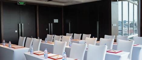 A conference room with white tables and chairs, equipped with water bottles and nameplates.
