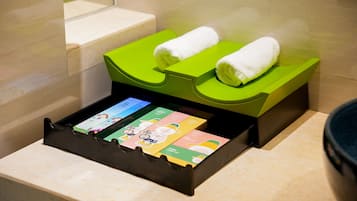 Ein Badezimmer mit einem grünen Handtuchwärmer, einer schwarzen Ablage mit Toilettenartikeln und einem weißen Handtuch auf dem Wärmer.