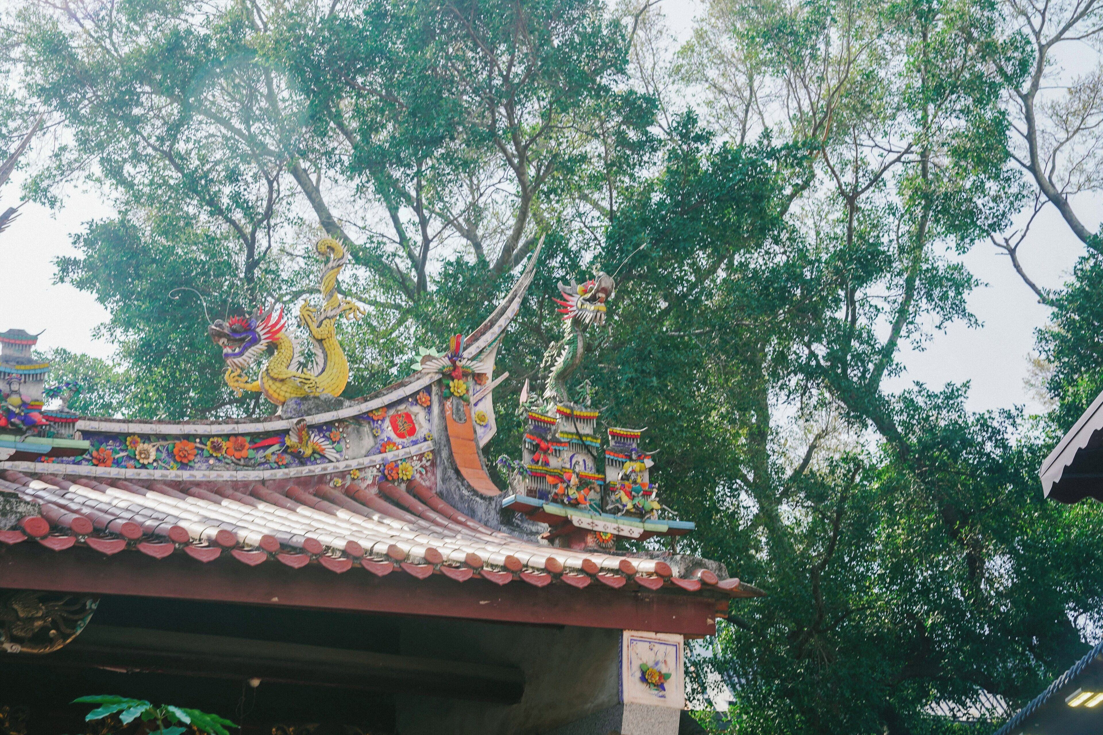 Un edificio tradicional con decoraciones ornamentales en el techo y una figura de dragón.