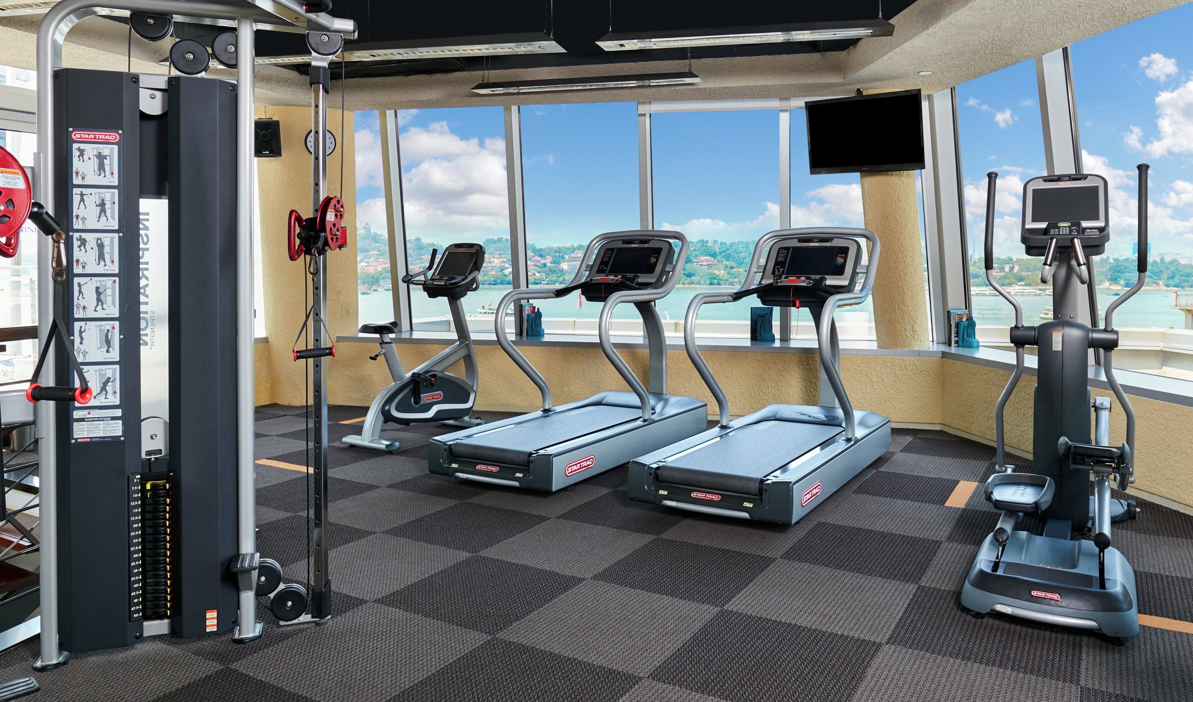 A gym with treadmills, a weight machine, and a TV screen.