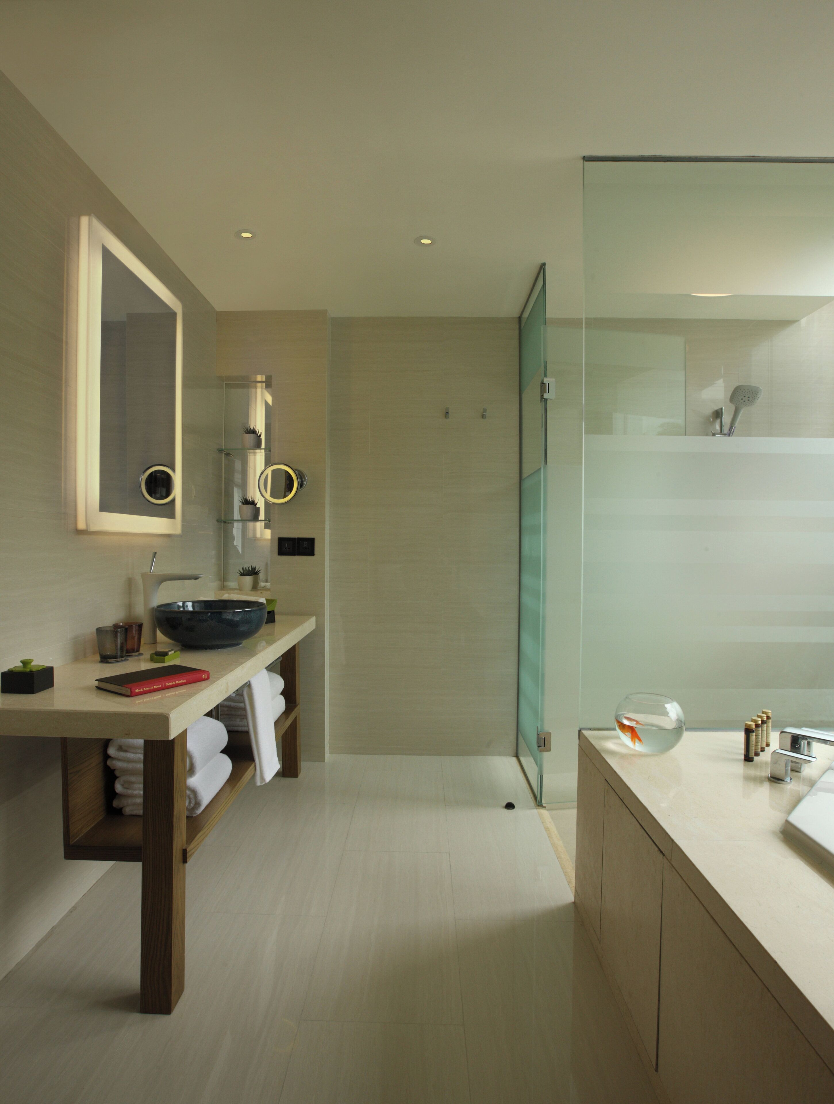Un baño moderno con cabina de ducha de vidrio, tocador con espejo grande y lavabo.