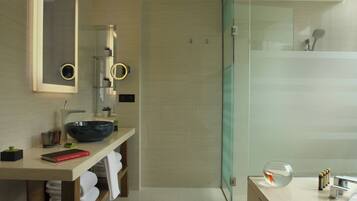 Un baño moderno con cabina de ducha de vidrio, tocador con espejo grande y lavabo.
