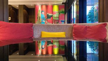 A lobby with a reflective floor, a central seating area with a yellow cushion, and colorful vertical panels in the background.