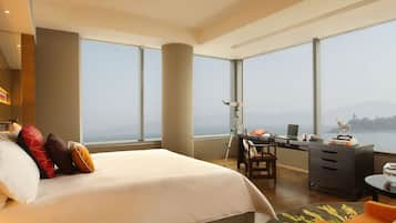 Una habitación de hotel moderna con una cama grande, un escritorio con una computadora portátil y vista al mar.