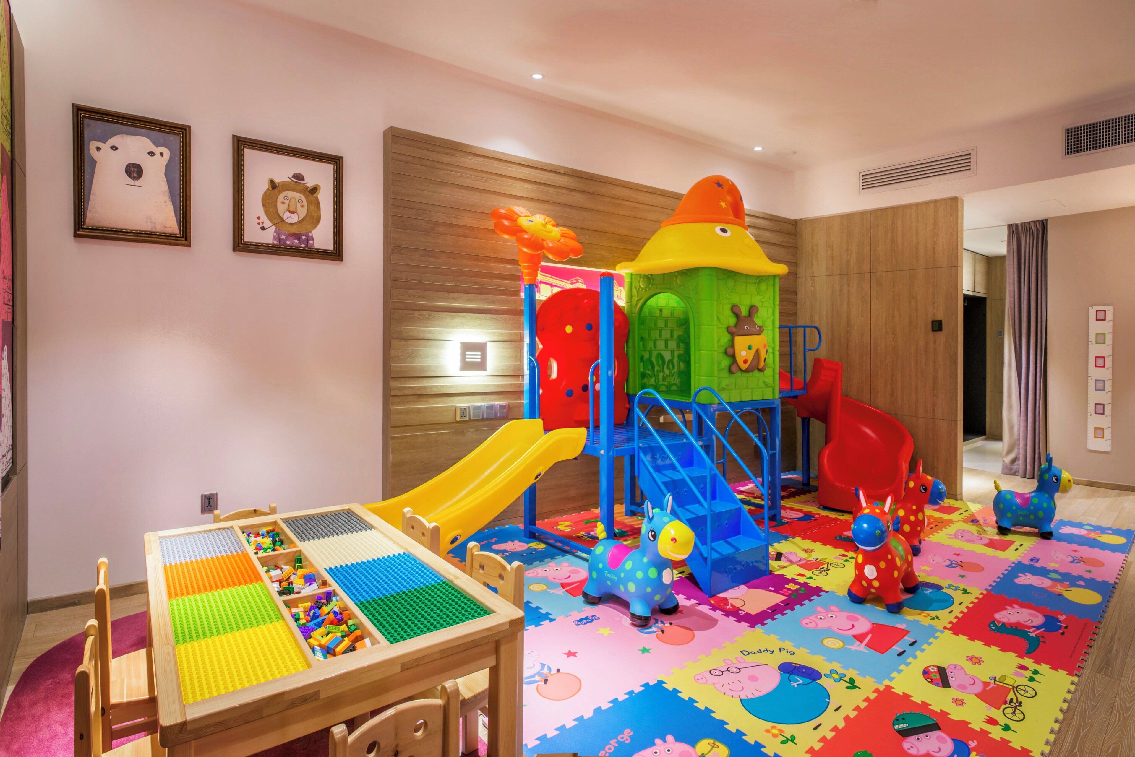 Zona de juegos infantiles con tobogán, estructura para escalar y una mesa con bloques de construcción.