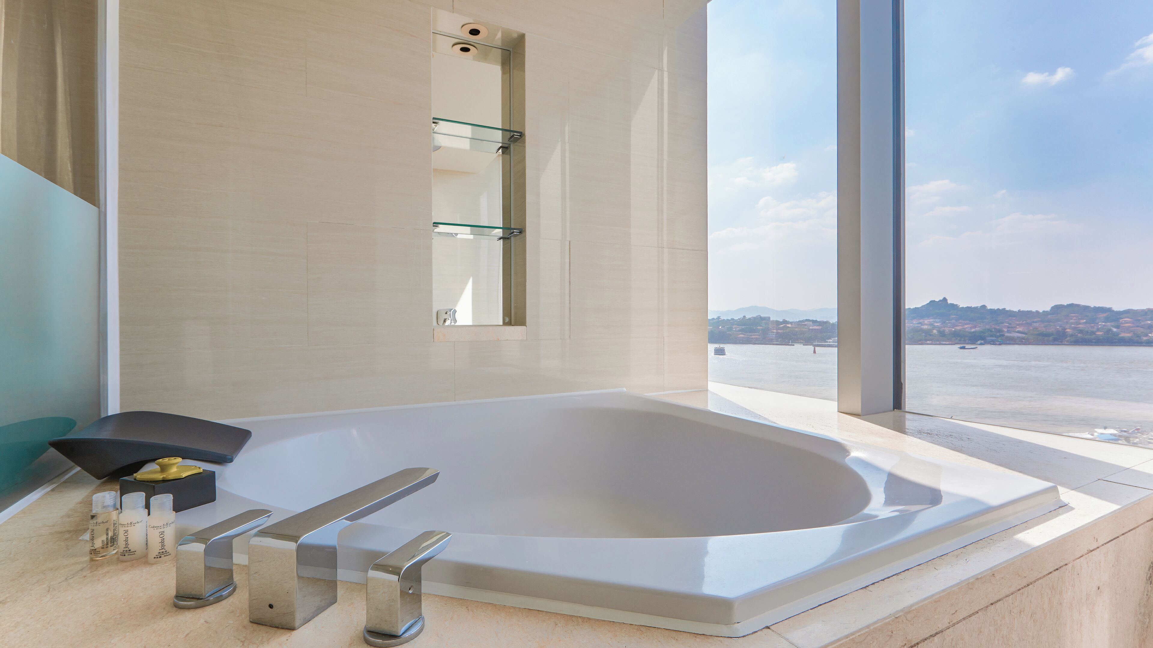 A modern bathroom with a large bathtub, a glass shower enclosure, and a view of a cityscape through large windows.