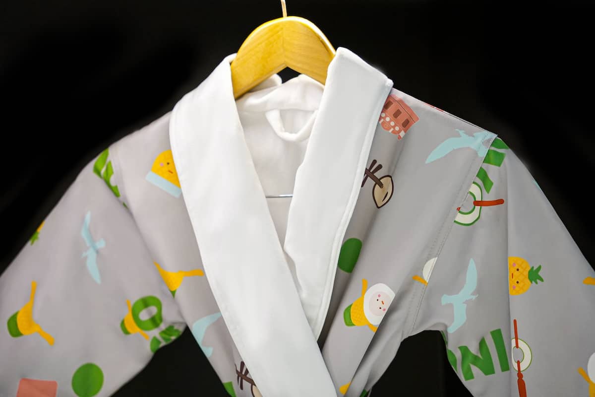 Una camisa blanca amb dibuixos de colors penjada en una perxa.