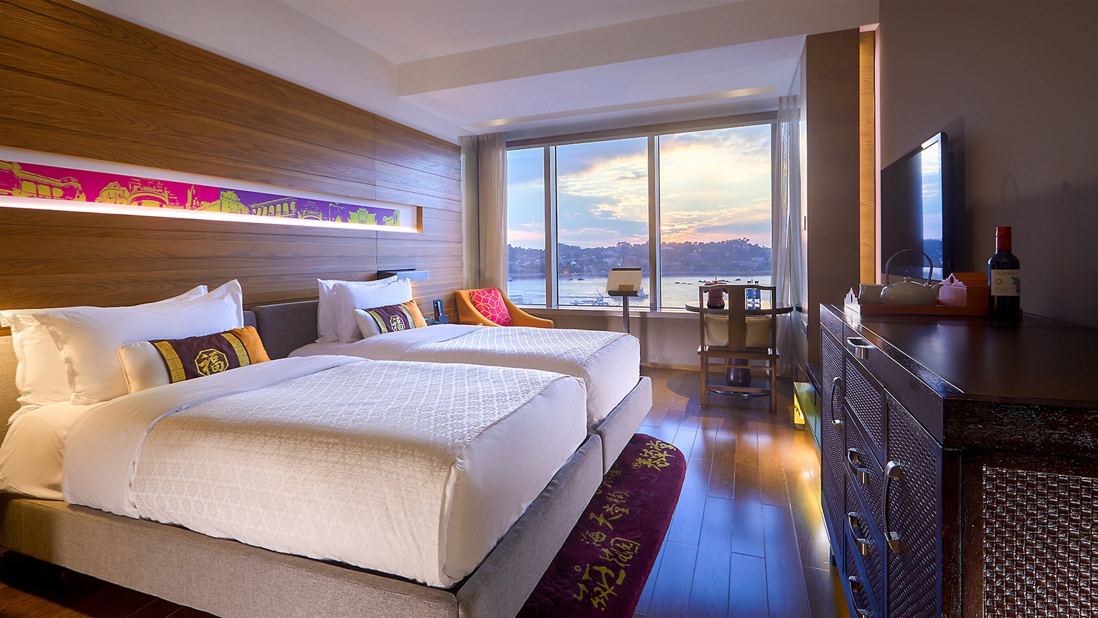 Habitación de hotel con dos camas, un ventanal con vistas, televisor y minibar.