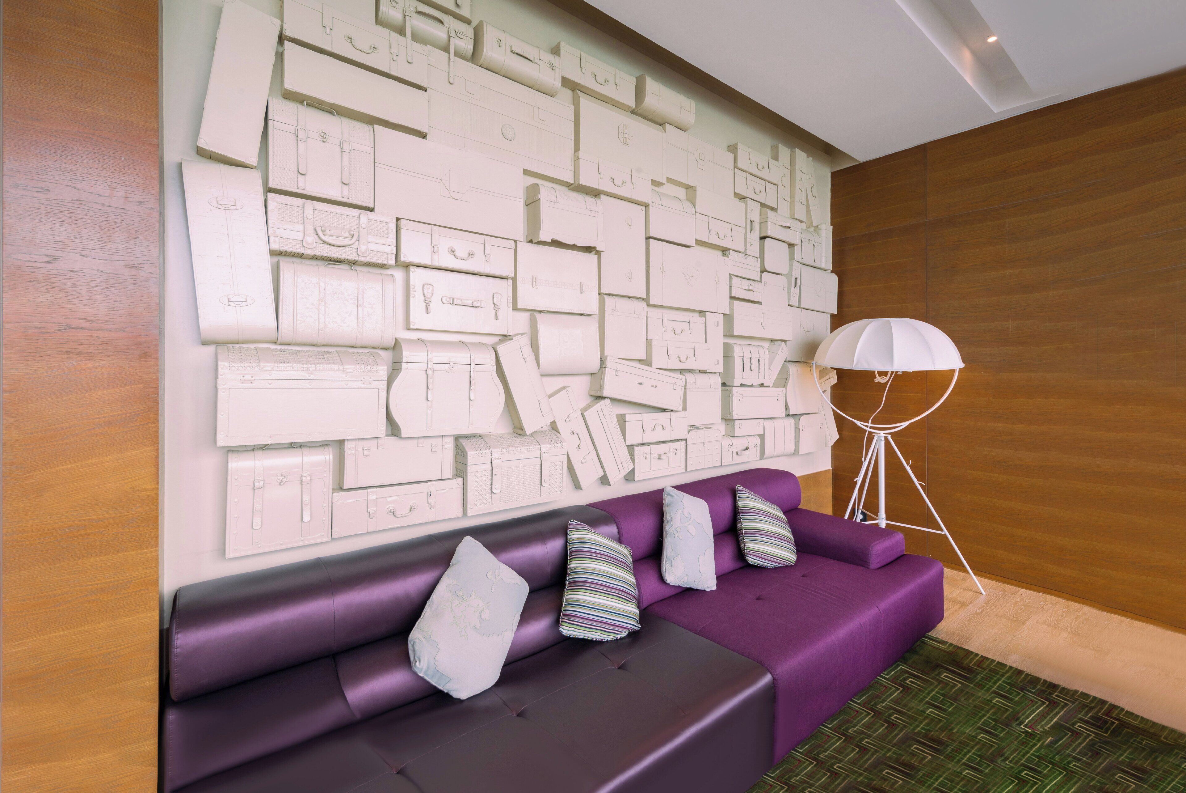 Ein modernes Zimmer mit einem violetten Sofa und einer Wand, die mit Skizzen von Koffern in Weiß verziert ist.