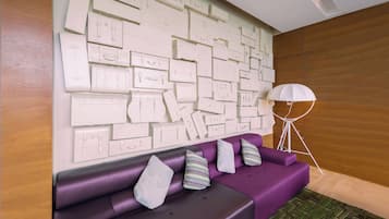 Ein modernes Zimmer mit einem violetten Sofa und einer Wand, die mit Skizzen von Koffern in Weiß verziert ist.