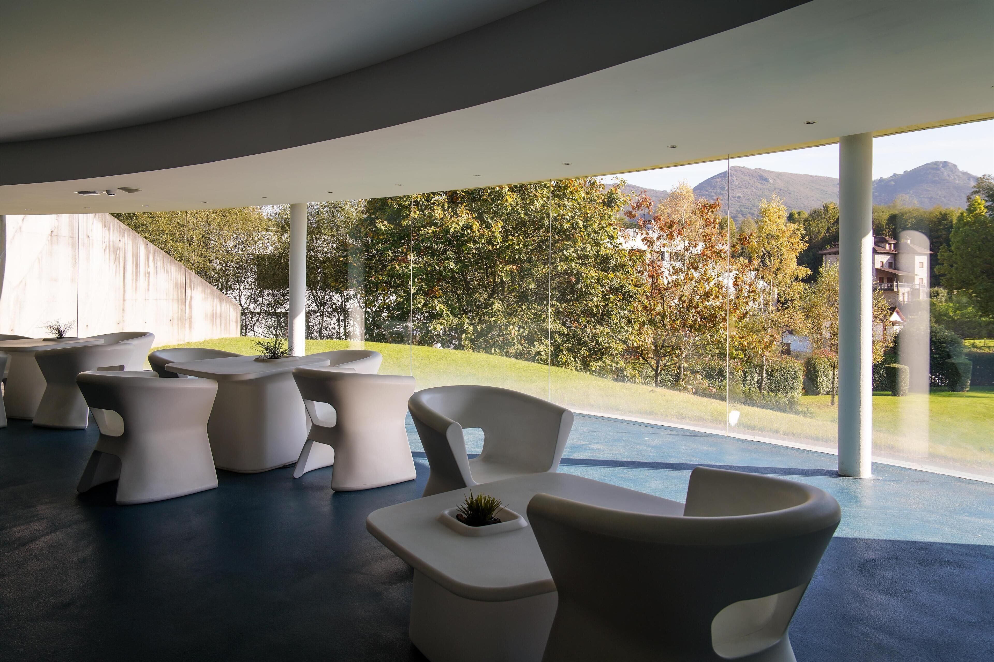 Un espace de détente moderne, avec des meubles blancs et une vue sur un paysage montagneux.