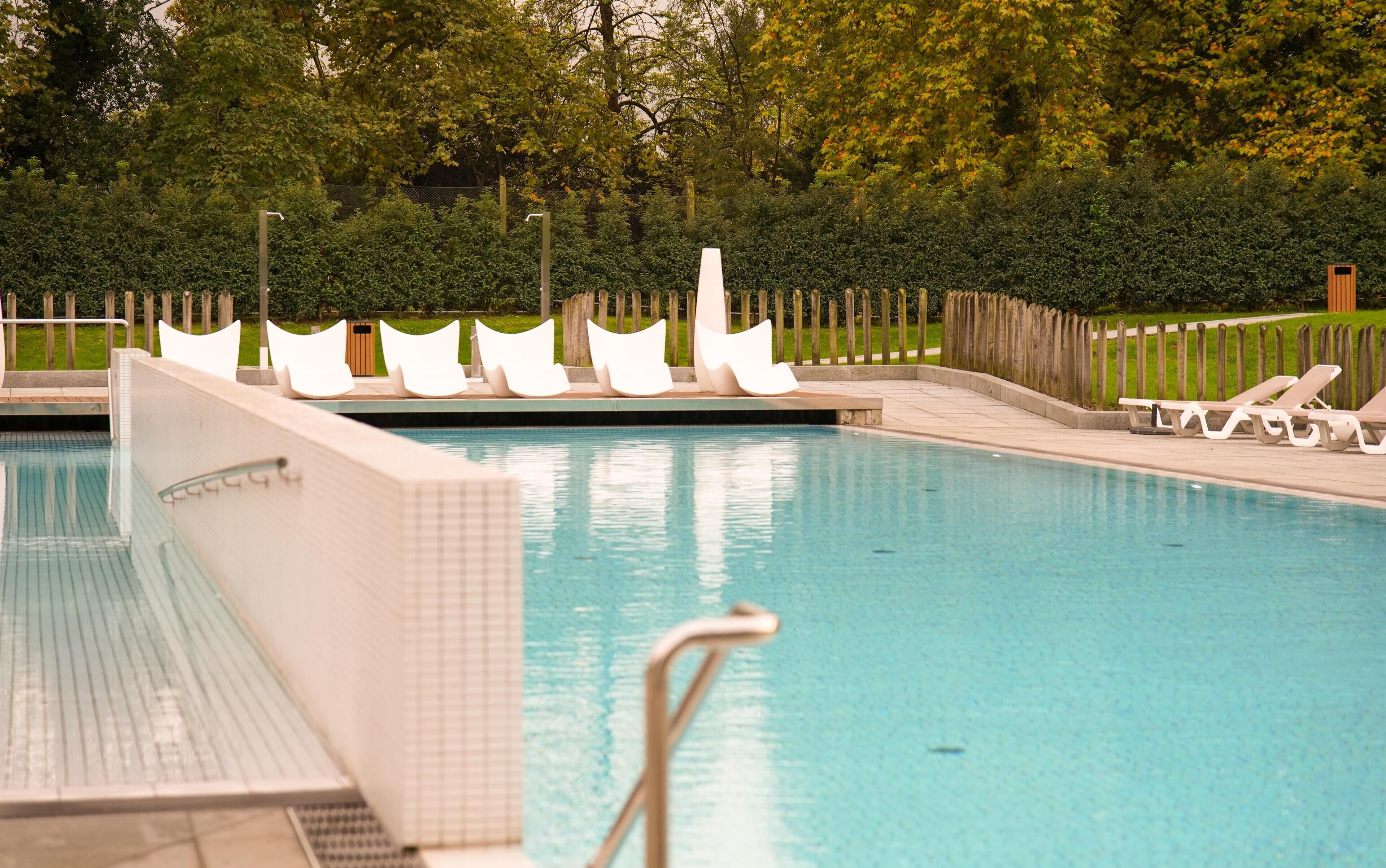 Una piscina amb gandules blanques i una tanca de fusta.