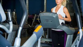 A person using a treadmill in a gym with various exercise equipment.