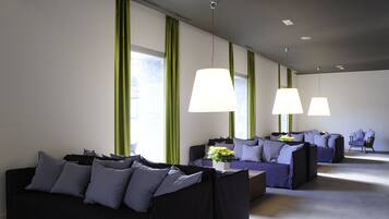 A modern hotel room with a black sofa set, green curtains, and pendant lighting.