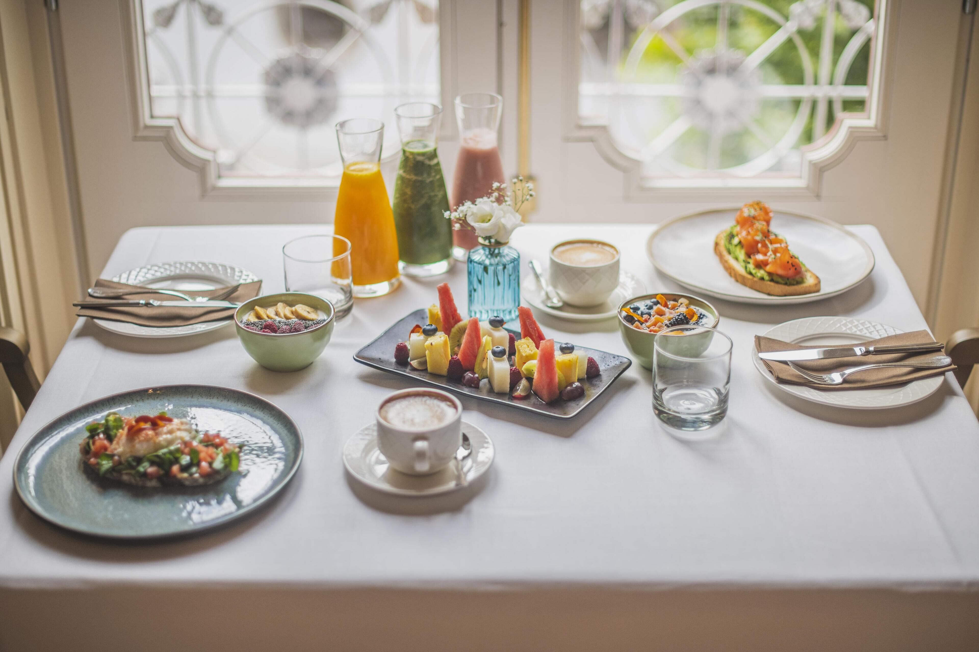 Une table de petit-déjeuner avec divers plats, boissons et une tasse de café.