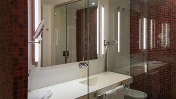 A modern bathroom with a glass shower enclosure, a white sink, and a visible towel rack.