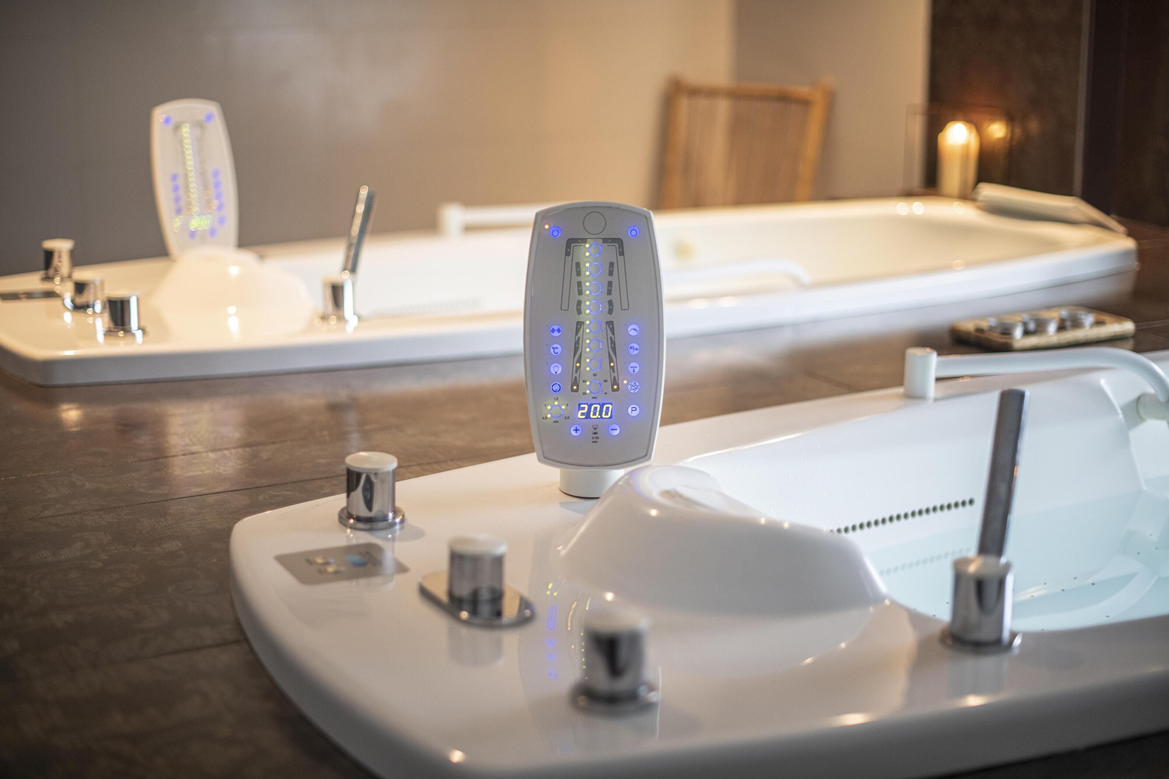Une salle de bain moderne dotée d’un panneau de commande numérique pour la douche, d’une baignoire et d’un espace douche séparé.