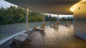 Een overdekt terras met houten vloer en witte leuningwerken.