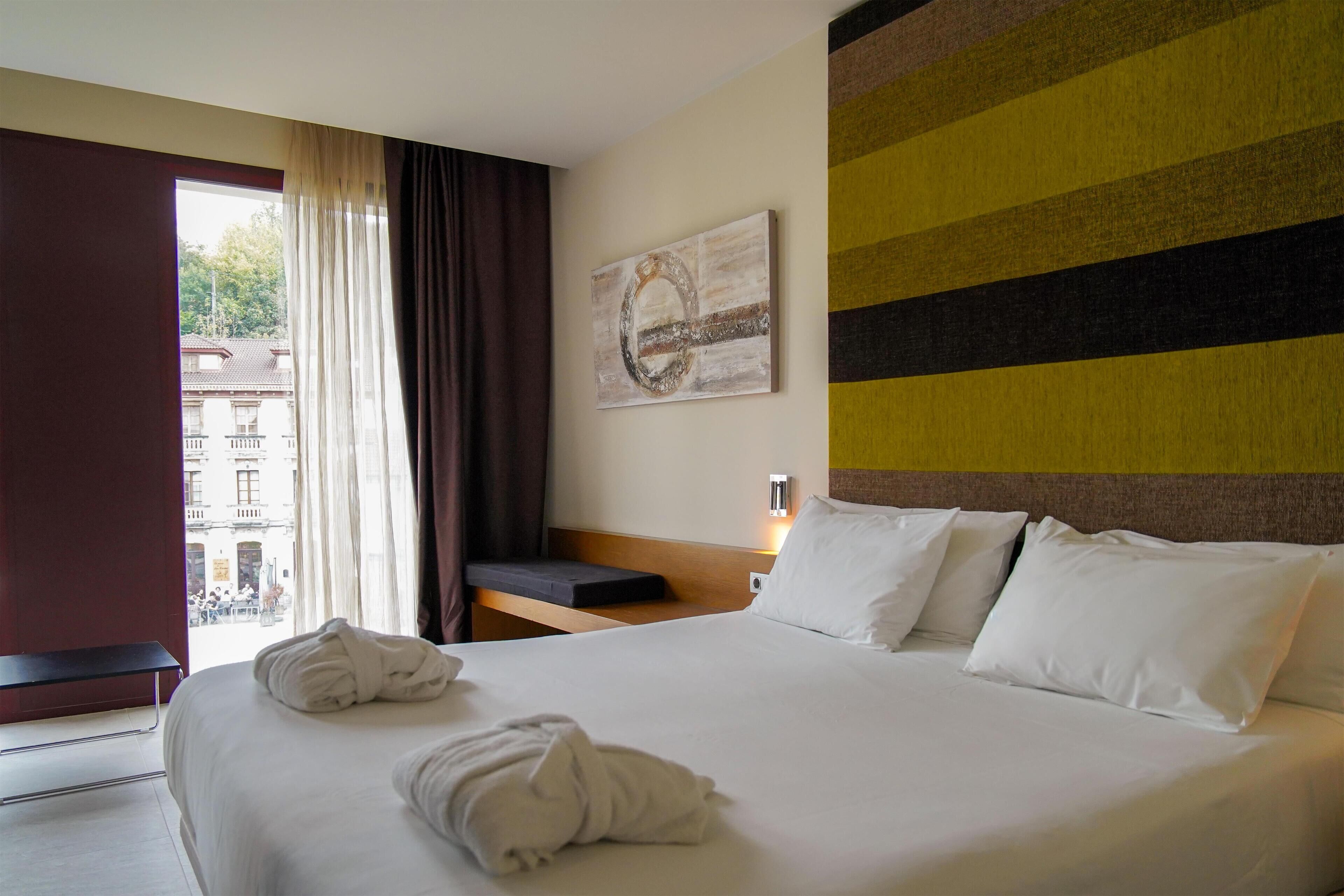 Habitación de hotel con una cama grande, vistas de la ciudad y un cuadro en la pared.