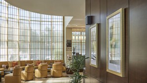 Un hall amplio con ventanas grandes, asientos de cuero, un mostrador de recepción y una planta en maceta.