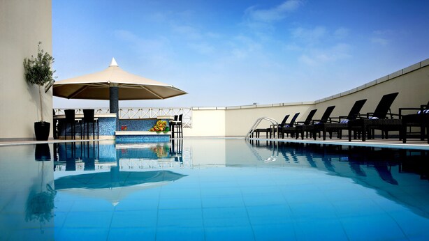 Una piscina azul cristalina con sillas de descanso y una zona de estar cubierta.