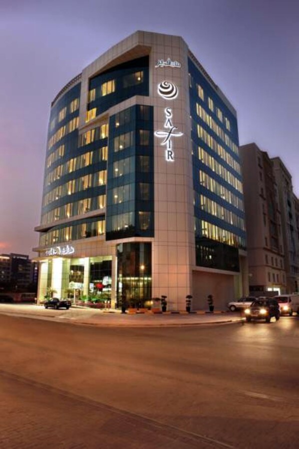 A modern hotel with a curved facade, multiple floors, and illuminated windows.