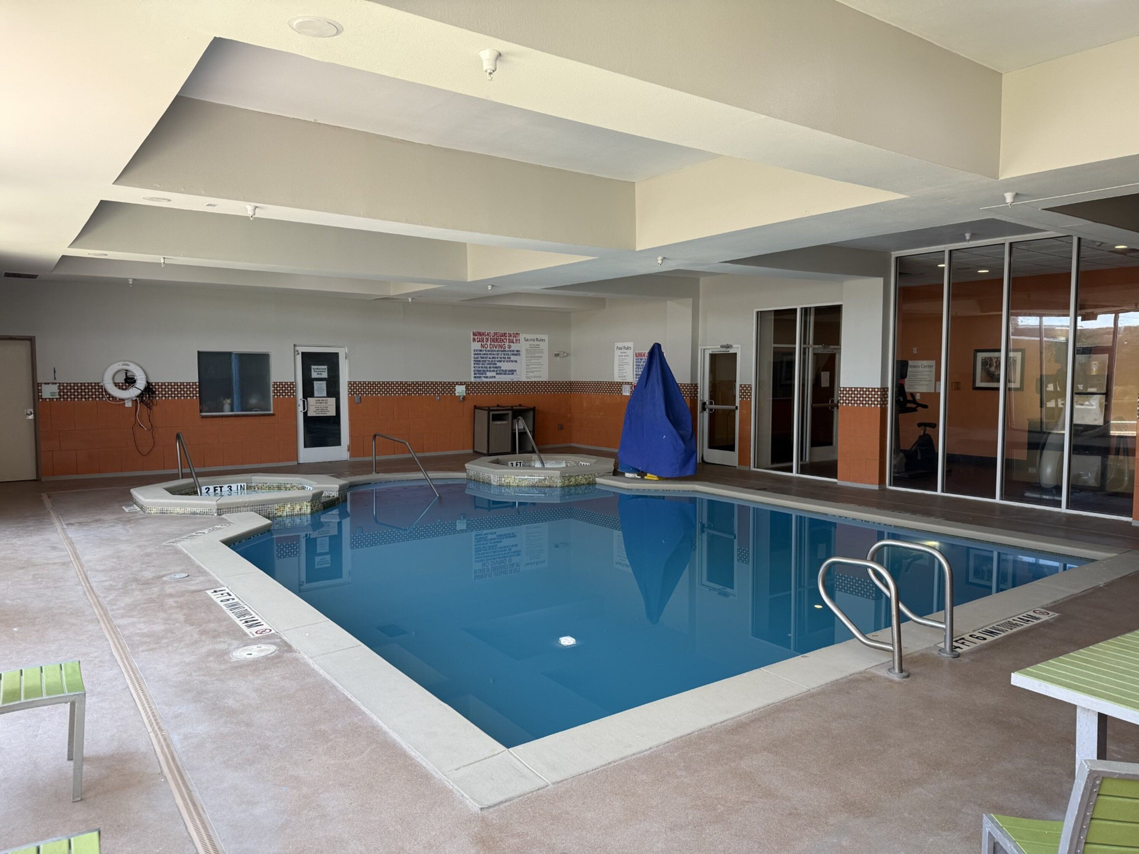 An indoor swimming pool with multiple lanes, safety equipment, and a lifeguard chair.