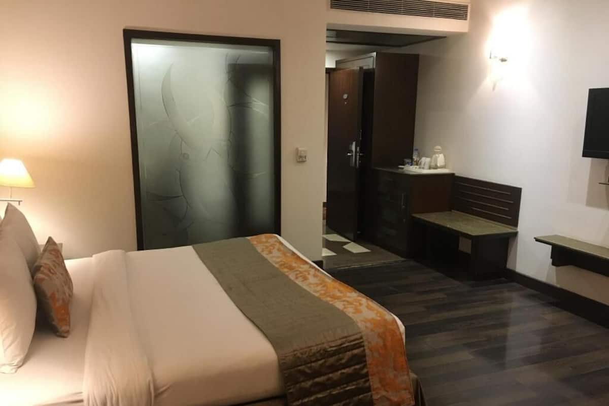A hotel room with a bed, a desk, a chair, a wardrobe, and a bathroom.