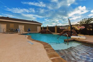 A swimming pool with a lifeguard stand, a changing room, and a covered area.