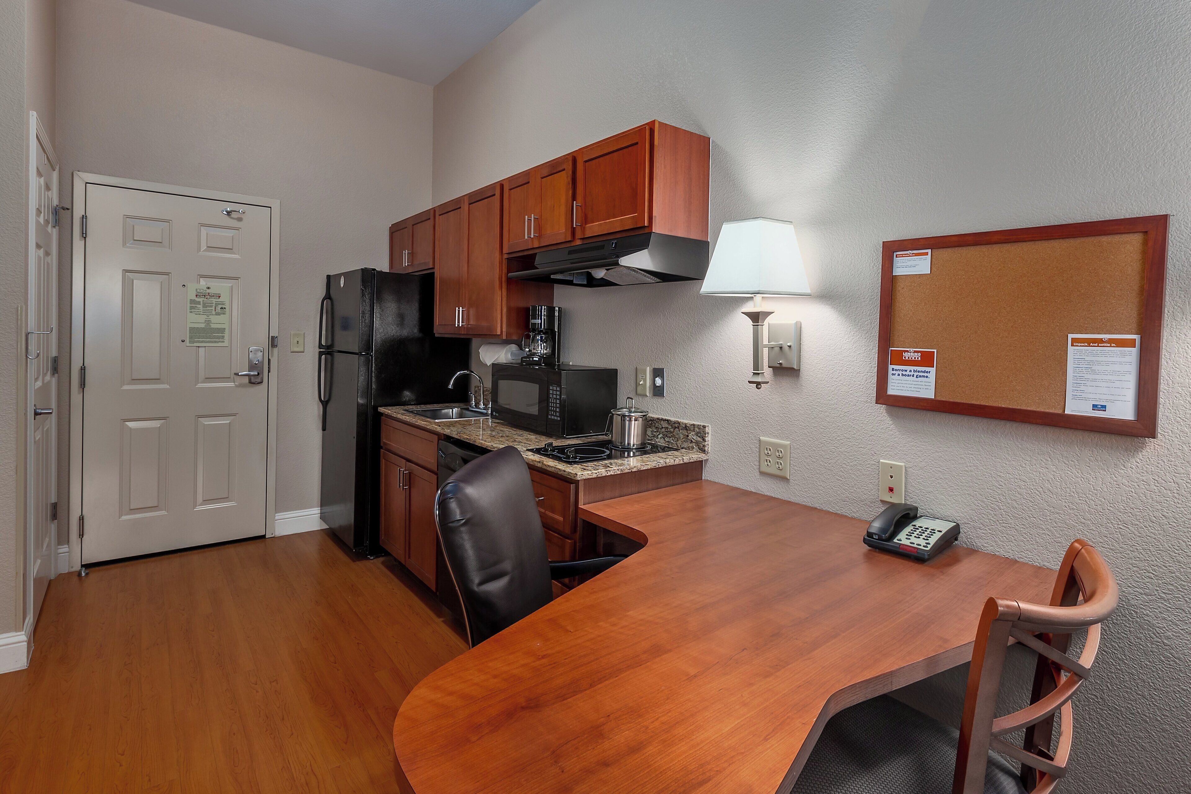 A compact kitchen with a refrigerator, microwave, coffee maker, and a dining table with chairs.