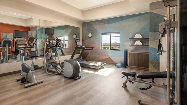 A gym with cardio machines, a bench press, and a mirrored wall. - Candlewood Suites Decatur Medical Center by IHG (Decatur)