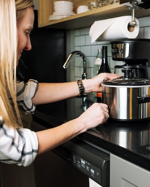 A person using a smart kitchen appliance with a digital display, a water dispenser, and a coffee maker.