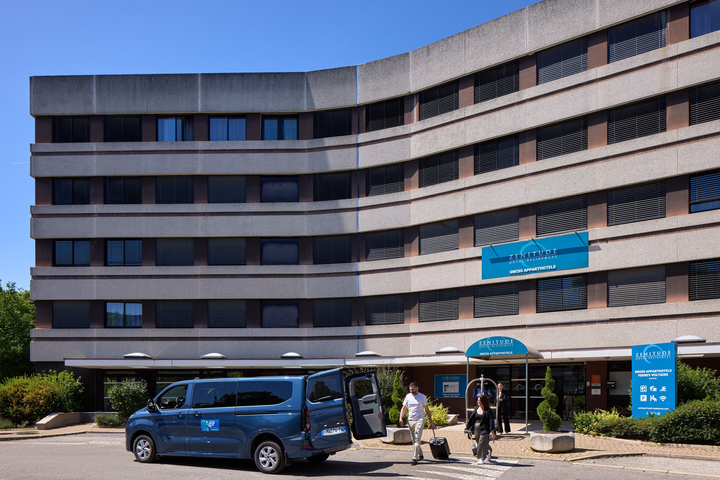 A multi-story hotel with a modern design, featuring a prominent sign for the Swiss apartments.