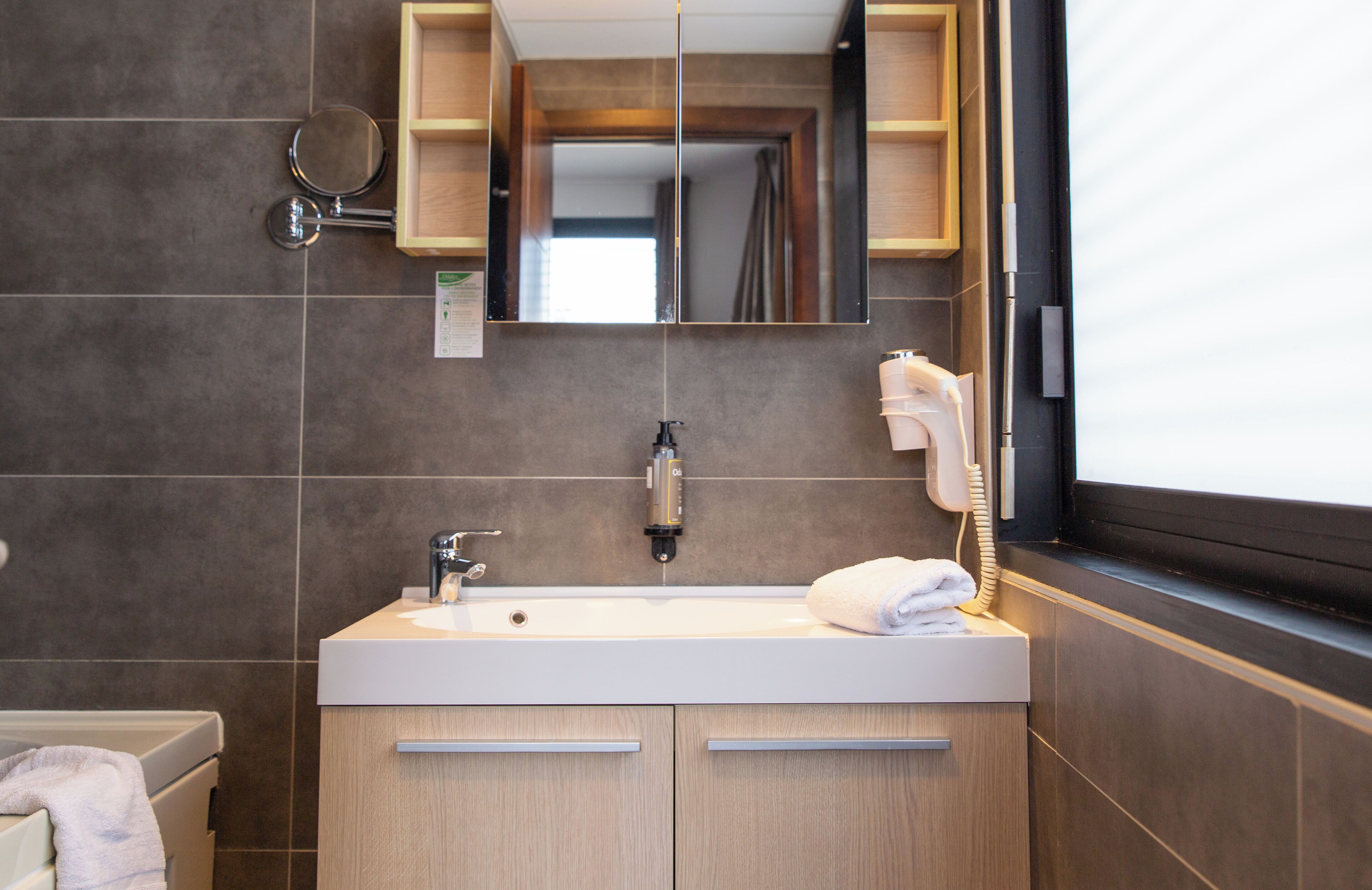 Un bany modern amb un mirall gran, un lavabo i un escorredor de tovalloles.