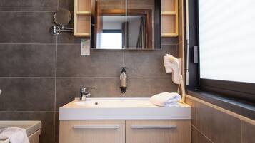 Un baño moderno con un espejo grande, un lavamanos y un perchero para toallas.