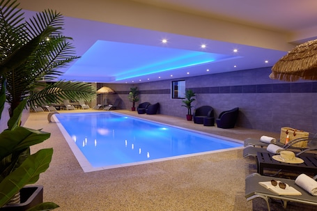 A swimming pool with lounge chairs and potted plants.. Zenitude Swiss Apparthotels