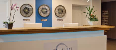 A reception desk with three wall clocks labeled 'New York,' 'Paris,' and 'Le Caire.'