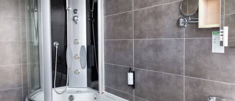 Un baño moderno con ducha de vidrio, una bañera independiente y un lavamanos con espejo.