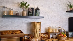 Un buffet de petit-déjeuner proposant une variété de pains, de viennoiseries et de fruits.