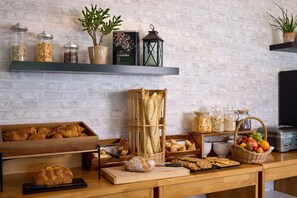 Ein reichhaltiges Frühstücksbuffet mit verschiedenen Brotsorten, Gebäcken und Früchten.