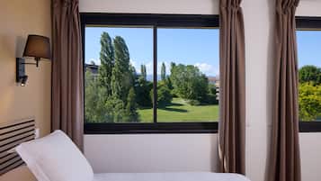 Una habitación de hotel con un ventanal grande, una cama y una lámpara de pared.