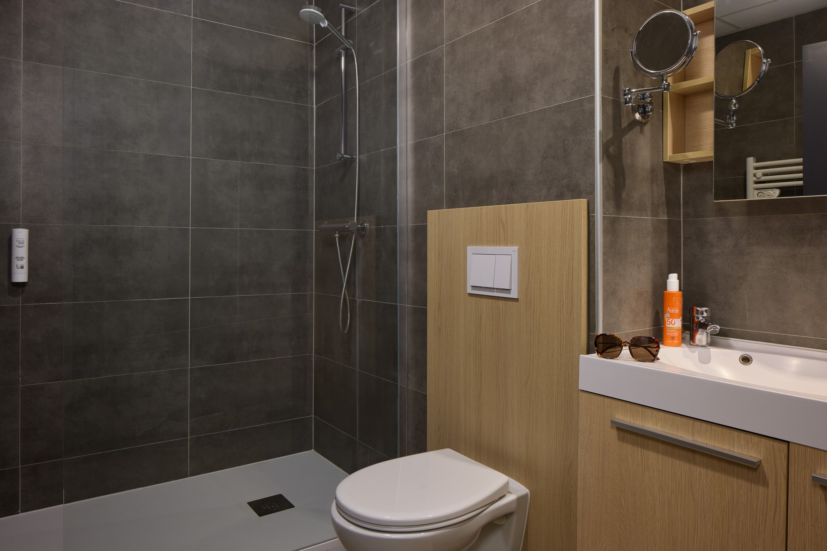 Een moderne badkamer met een douche, toilet en wastafel met spiegel.
