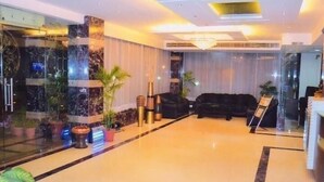 A modern lobby with a marble floor, a black sofa, and potted plants. - Hotel Hari Heritage (Haridwar)