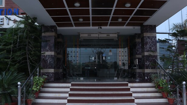 A hotel entrance with marble steps, a glass door, and potted plants. - Hotel Hari Heritage (Haridwar)