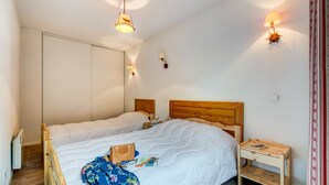 Un dormitorio con una cama grande, dos mesitas de noche, un armario y una pequeña mesita con una lámpara.