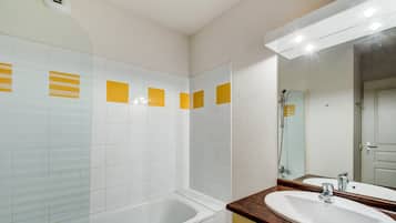 A bathroom with a bathtub, a sink, and a mirror.