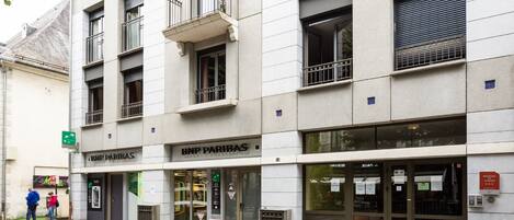 Un edificio con varias fachadas comerciales, incluyendo un cajero automático visible y un letrero de BNP Paribas.